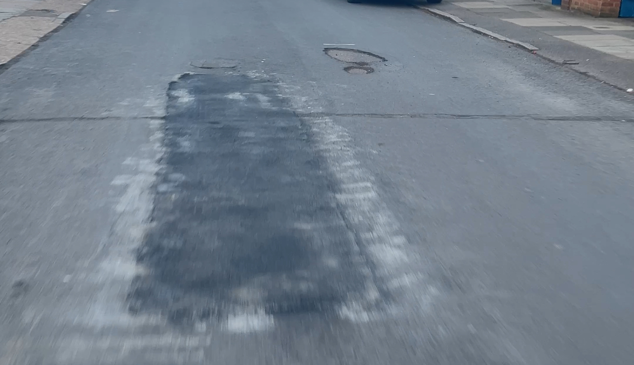 Lincoln Avenue — fretting and surface wear visible adjacent to a recent repair and utility covers