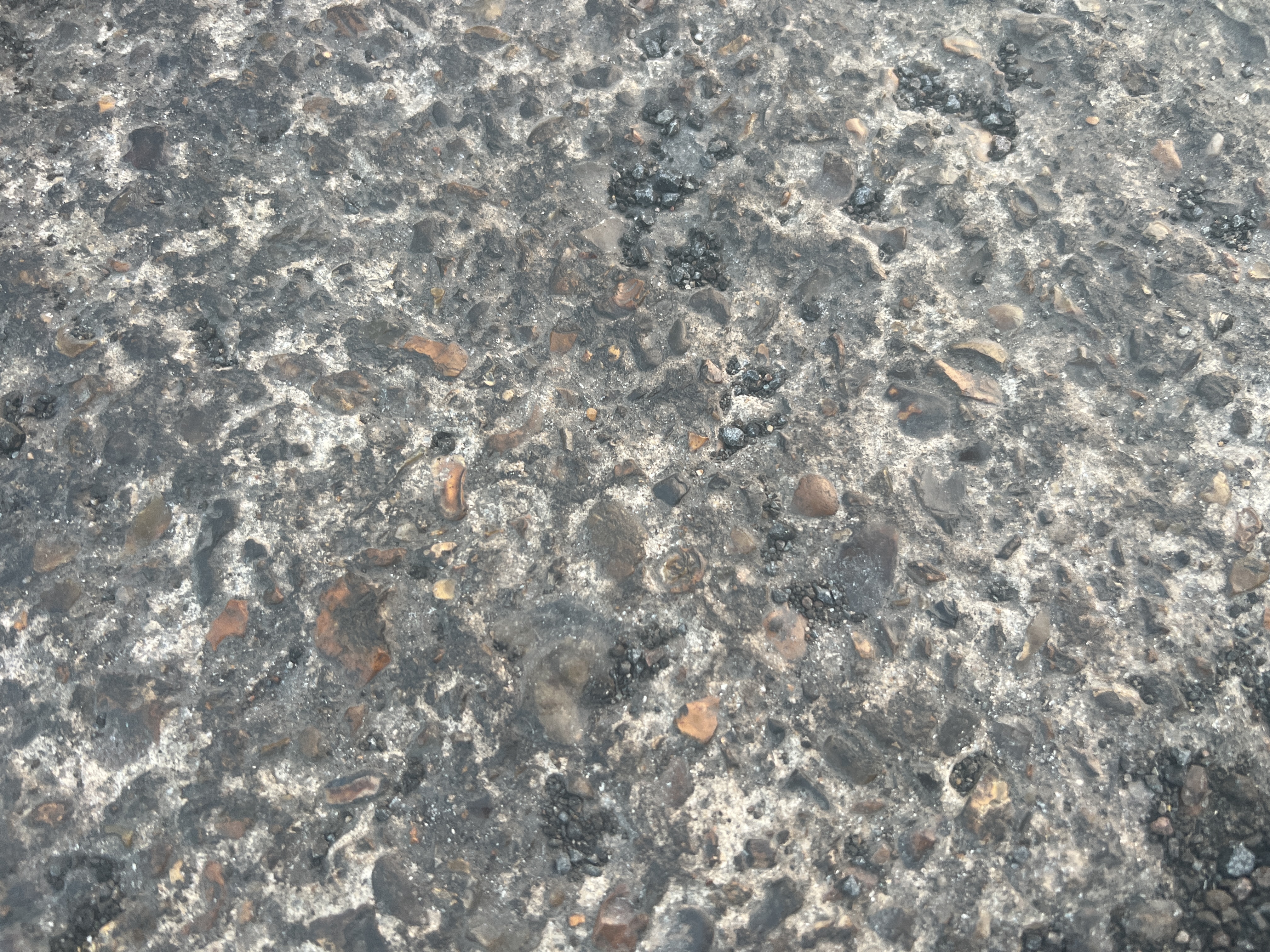 Close-up view of asphalt surface showing fretting where aggregate has begun to loosen from the binder